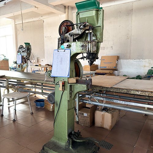 Riveting machine securing joints on folding commode chair frame
