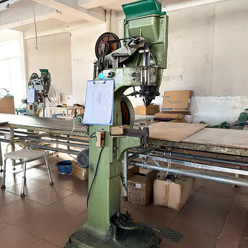 Riveting machine securing joints on folding commode chair frame